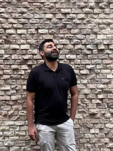 Rahul Sengupta laughing candidly against a stone wall